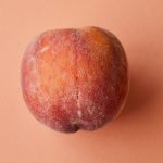 fresh juicy pink peach on pink surface
