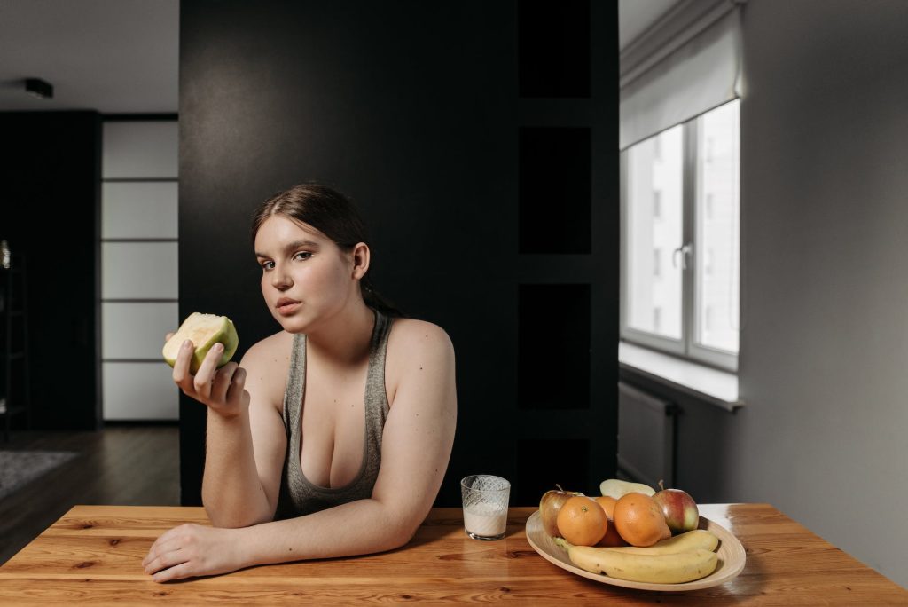 woman in gray tank top holding an apple