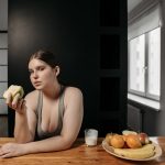 woman in gray tank top holding an apple